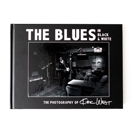 This image features the cover of "The Blues in Black & White," a photography book by Kirk West. The book's cover displays a monochrome photograph of a blues musician performing, which captures the essence of the blues culture.
